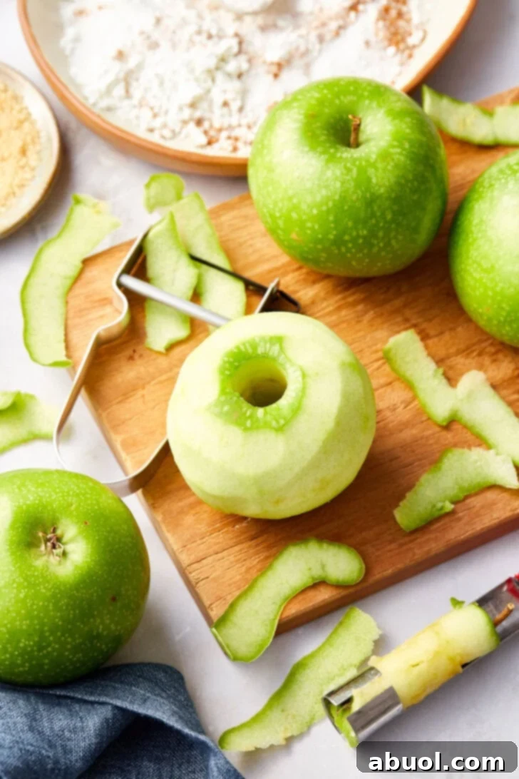 Green apples on a wooden cutting board being peeled. 