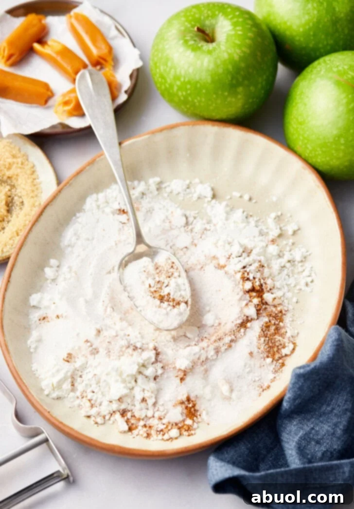 Flour and spice mixture for baked mini apple pies in white bowl.
