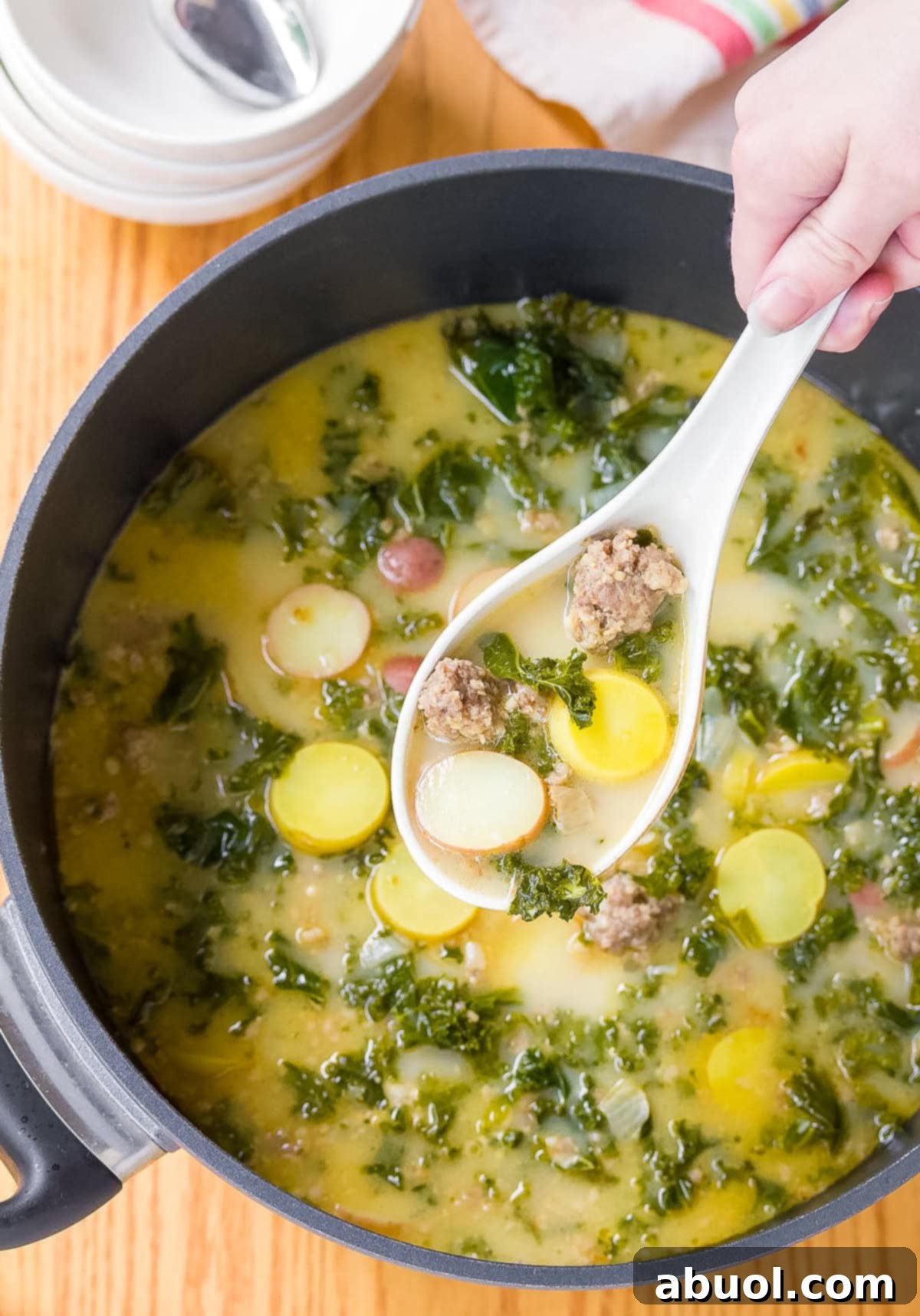 Parmesan Kale Soup - A white ladle holding a scoopful of kale soup over a soup pot.