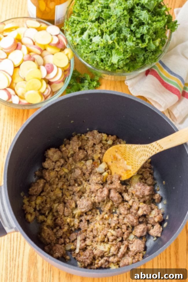Pork sausage in a saucepan with a wooden spoon.