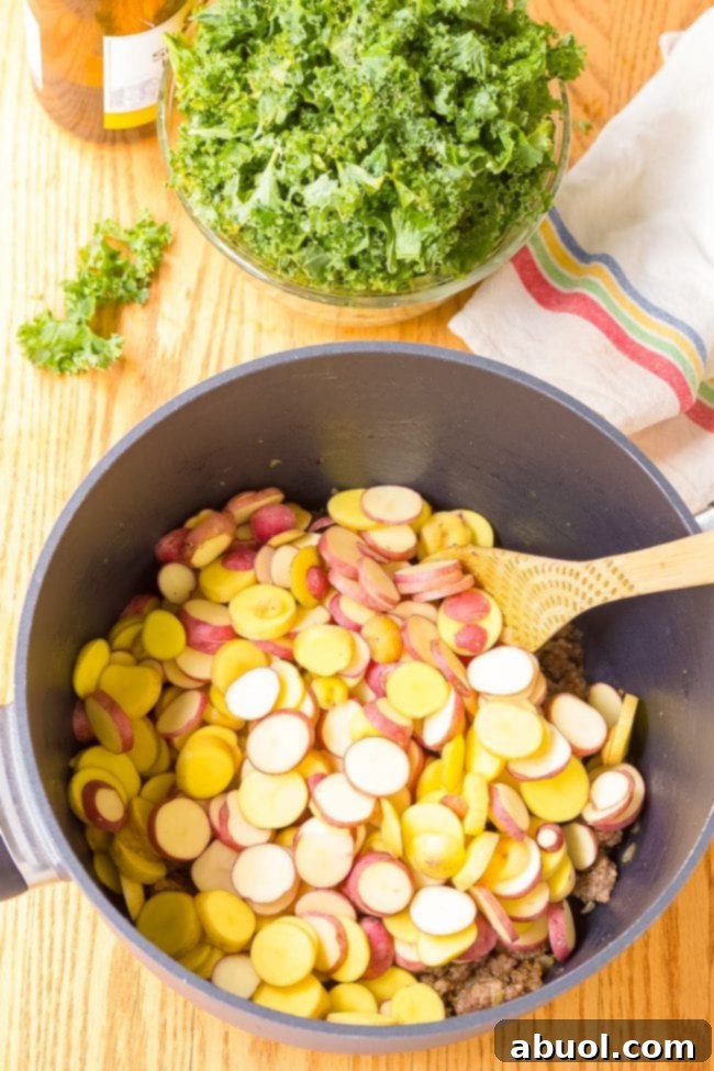 Sliced potatoes in a saucepan with a wood spoon.