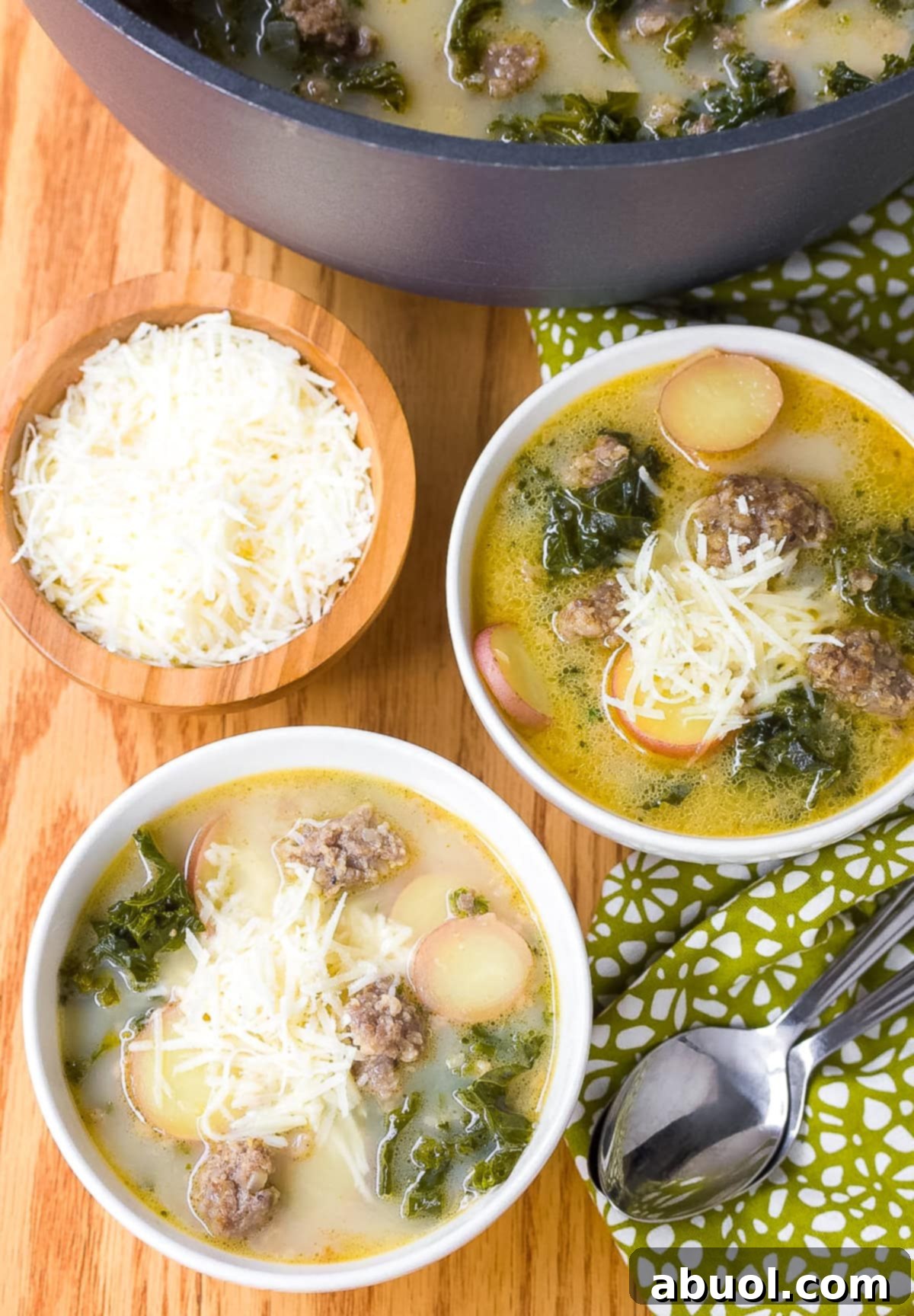 Two white bowls of sausage and kale soup.