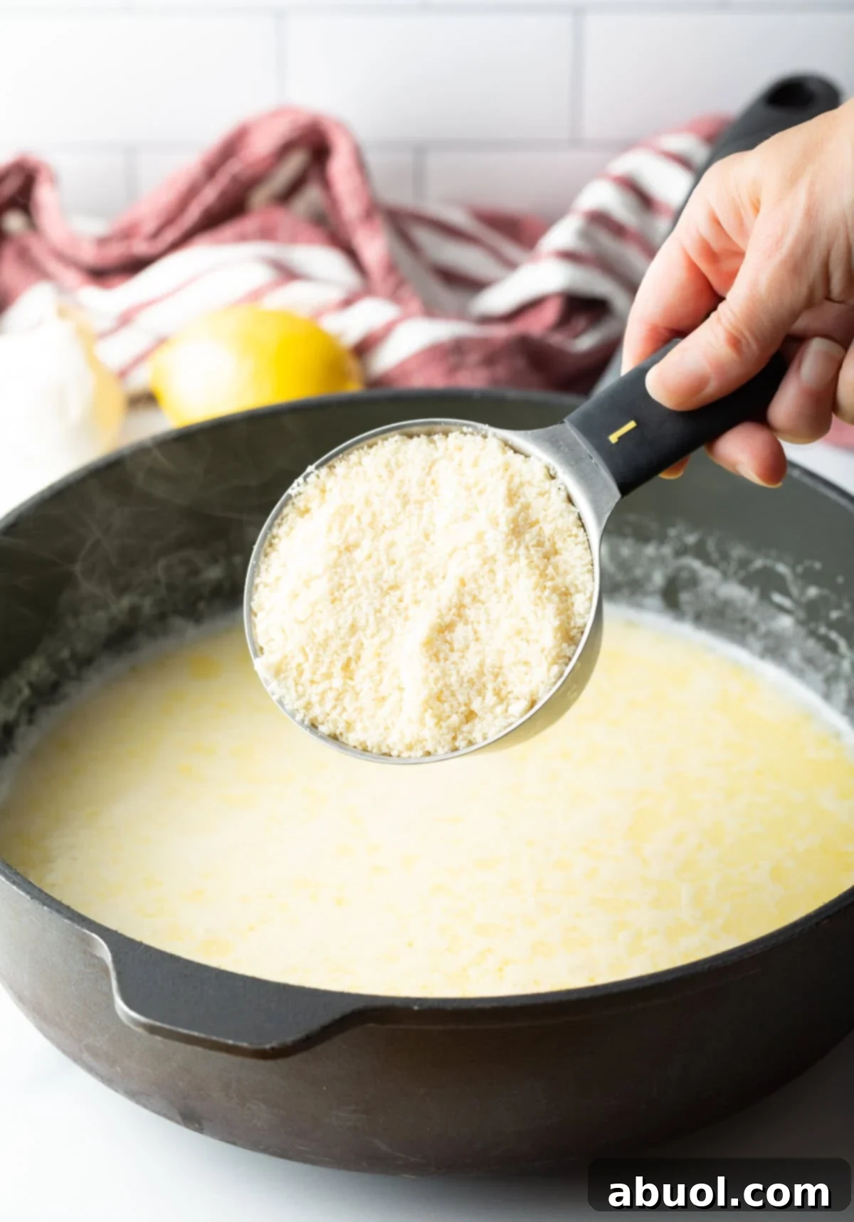 Freshly grated Parmesan cheese being added to creamy sauce