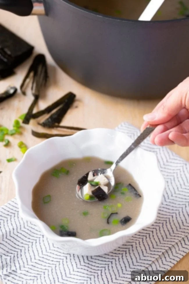 A steaming pot and bowl of homemade Japanese Miso Soup, garnished with green onions and tofu, ready to be enjoyed.