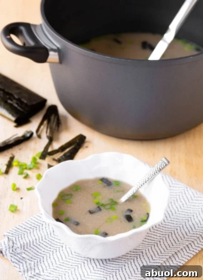 A close-up view of a single serving of Japanese Miso Soup in a ceramic bowl, garnished with cubed tofu and chopped green onions.