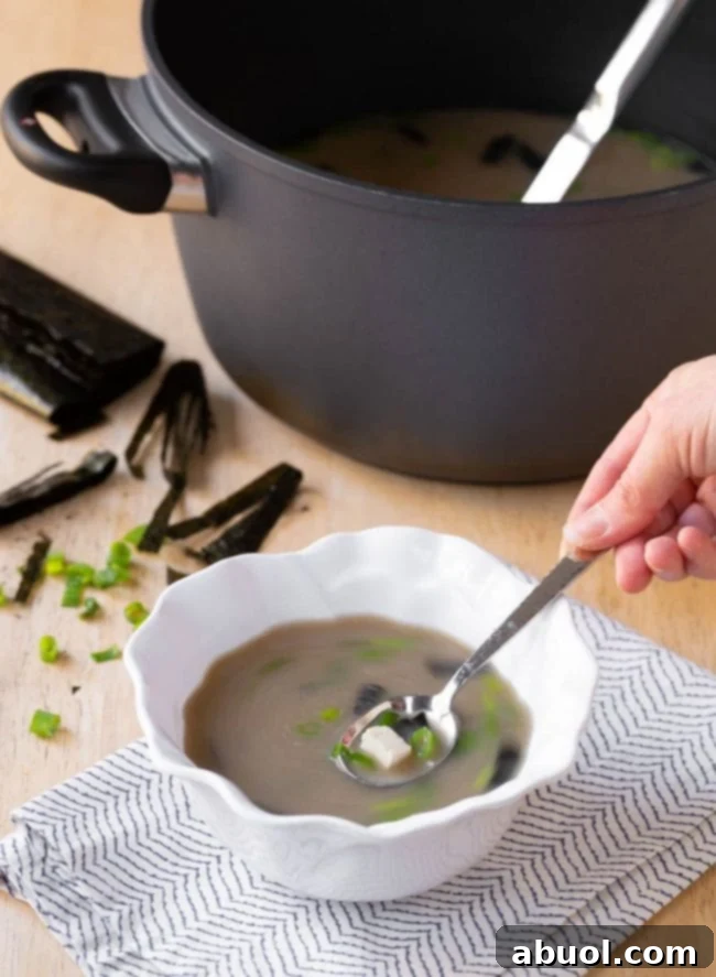 A close-up of a bowl of the finished 5-ingredient Japanese Miso Soup, ready to be eaten, with visible tofu, nori, and scallions.