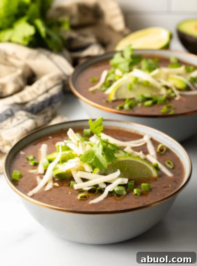 slow cooker black bean soup in a gray bowl with fresh garnishes like cilantro and lime