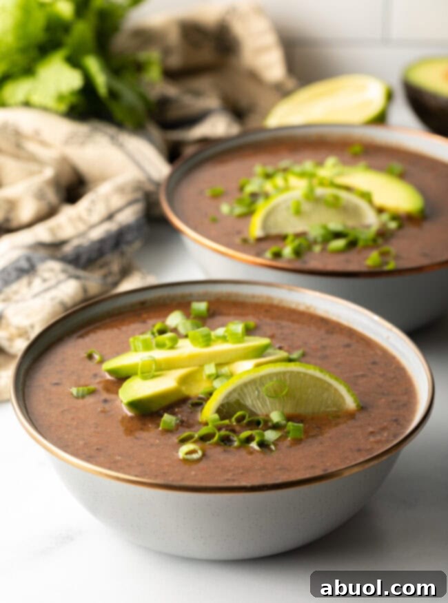 crock pot black bean soup with avocado, scallions, and lime wedges as toppings