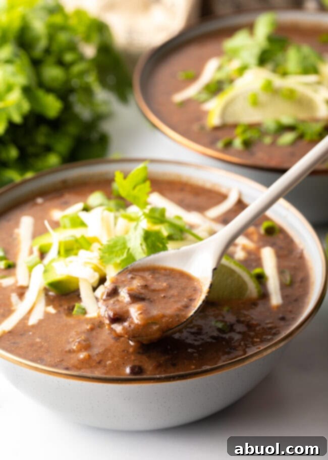 crock pot black bean soup being spooned into a gray bowl, showing its thick texture