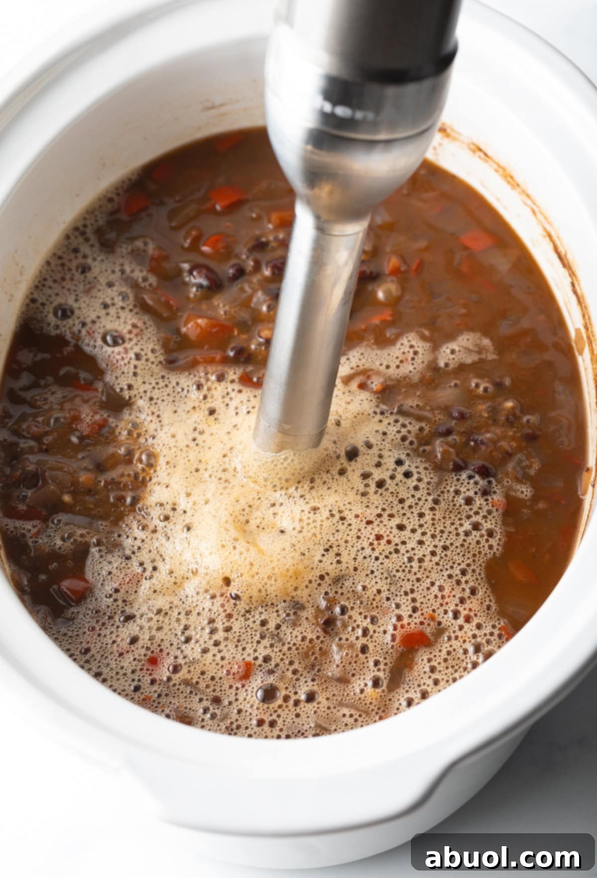 using an immersion blender to puree black bean soup directly in the crock pot