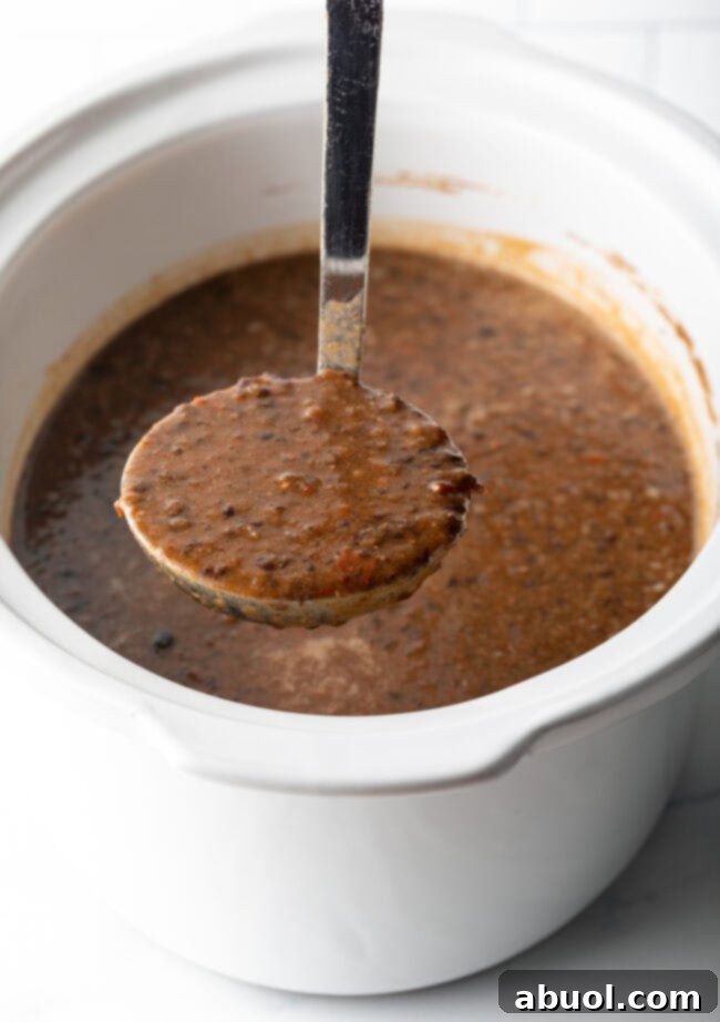 easy crockpot black bean soup being ladled from the pot into a bowl