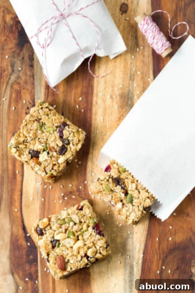 Square homemade granola bars on a wooden cutting board, showcasing their soft and chewy texture.
