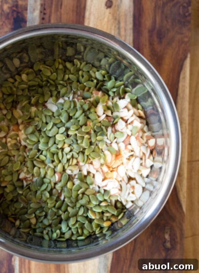 Seeds added to nut mixture in mixing bowl, enriching the granola bar base.