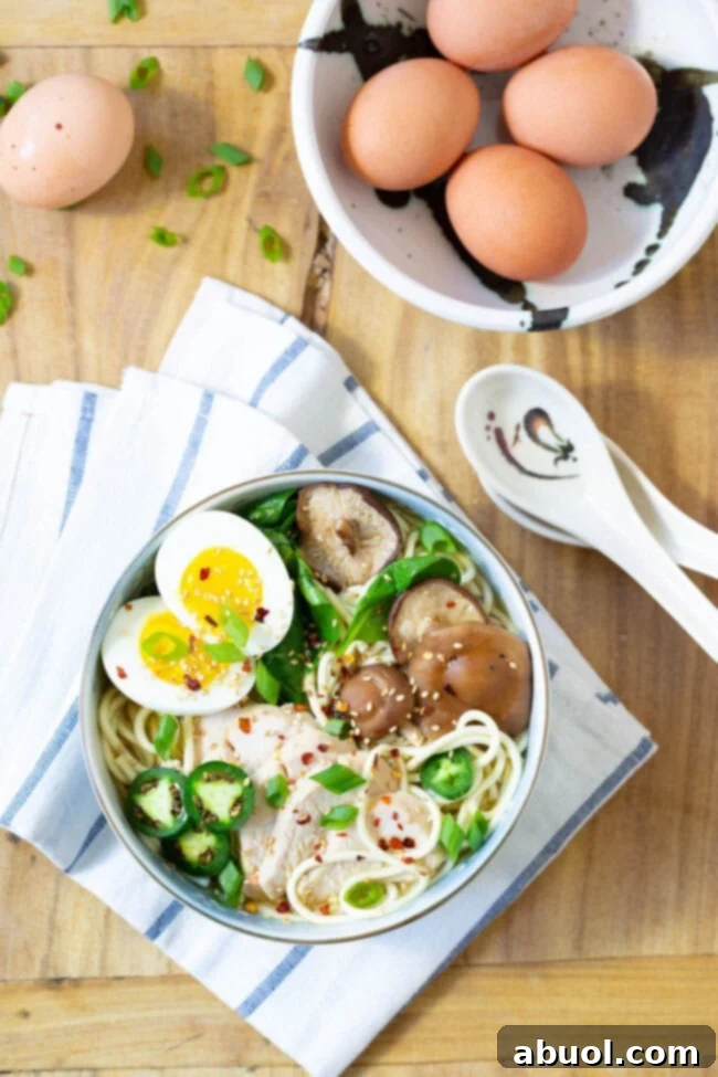 An overhead shot of two bowls of Slow Cooker Chicken Ramen Noodles, showcasing the rich broth, noodles, chicken, and various toppings.