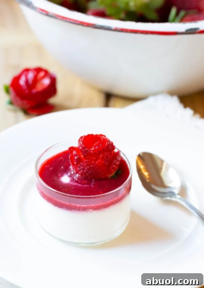 Small glass dish with silky Swedish cream topped with berry compote and strawberry rose, a perfect elegant dessert.