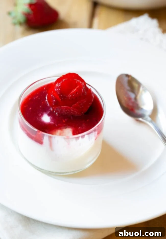 Small glass dish with silky white Swedish cream topped with vibrant berry compote and an artful strawberry rose, ready to be enjoyed.