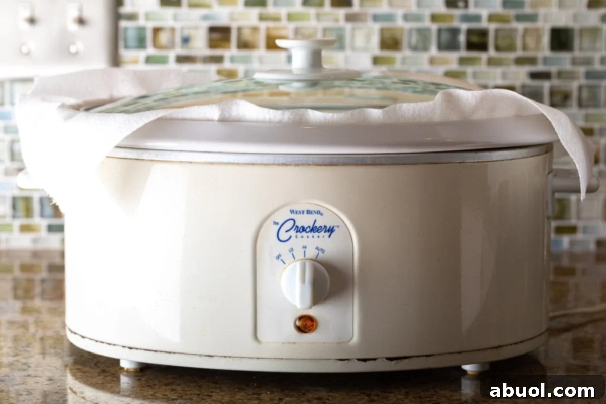 Side view of a classic white crock pot, showing its simple and functional design.