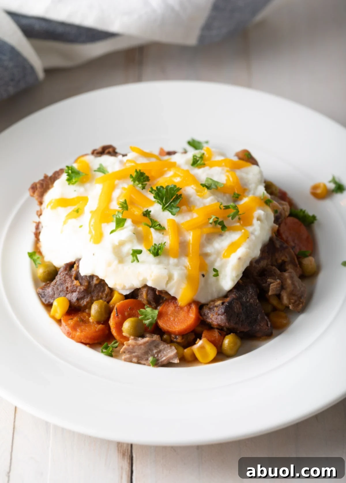 Shepherd's pie served on a rustic plate, topped with golden mashed potatoes and fresh herbs, ready to be enjoyed.