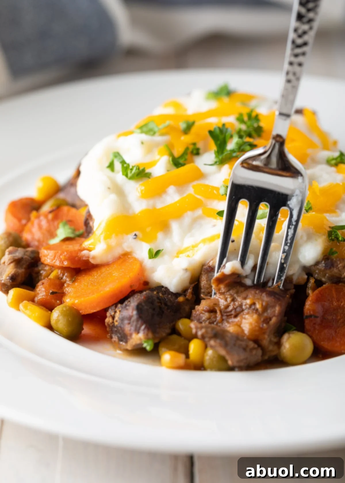 A fork taking a delicious bite out of a freshly served crockpot Shepherd's pie, highlighting the layers.