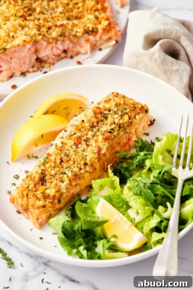 Golden brown parmesan crusted salmon fillet with a few bites missing, served beautifully on a plate.