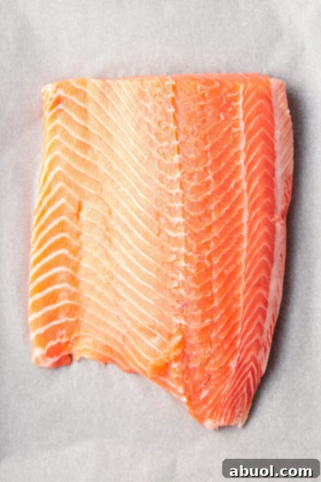 Raw wild salmon fillet seasoned and ready for the parmesan herb crust on parchment paper.