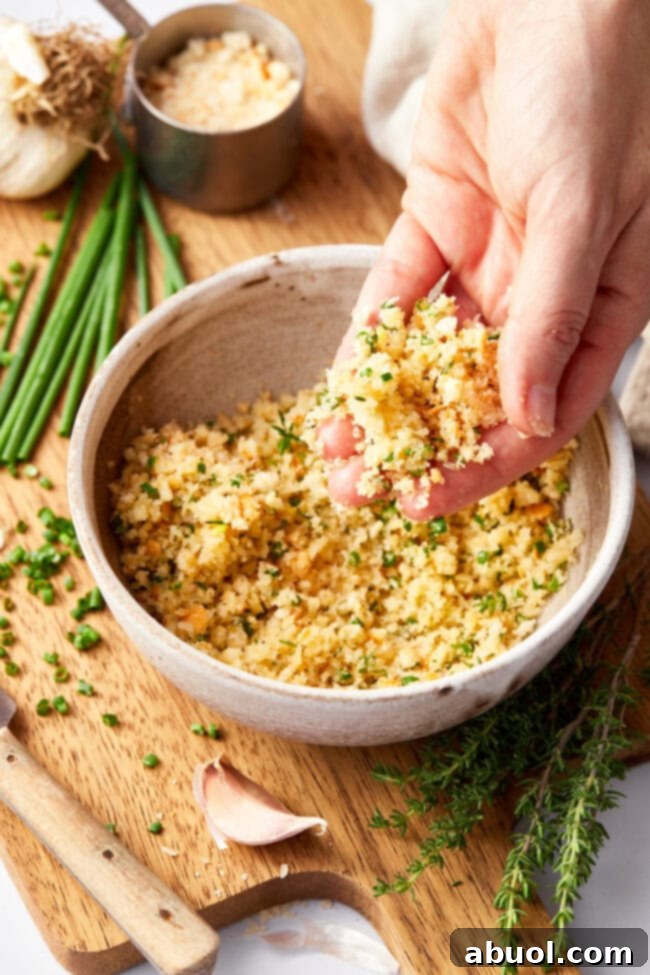 Parmesan herb breadcrumbs mixture in a bowl with melted butter, ready to be combined.