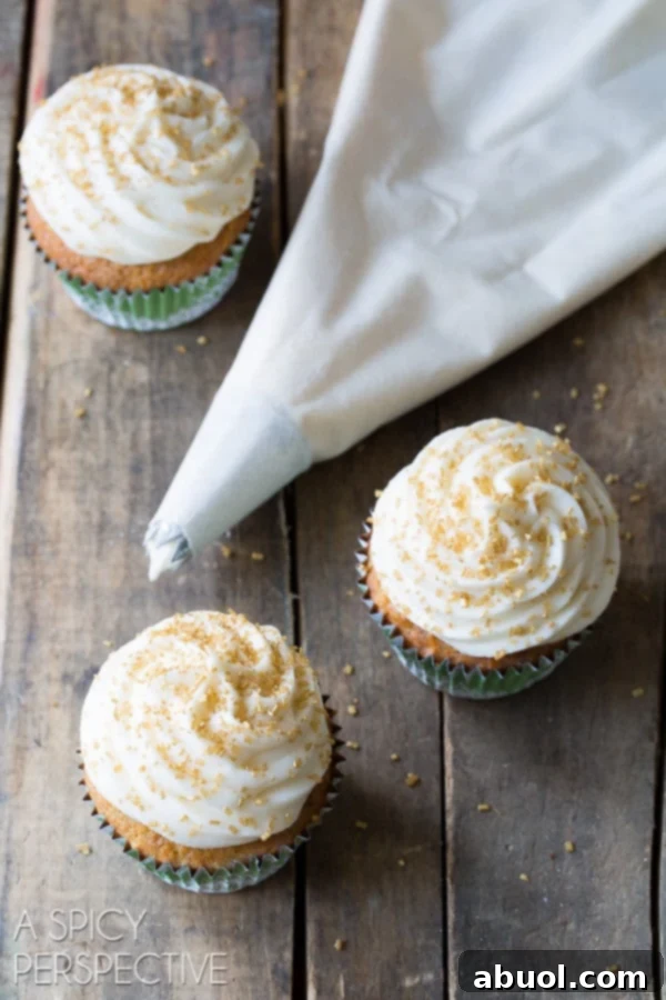 A piping bag ready to frost cupcakes, with several beautifully decorated hummingbird cupcakes nearby.