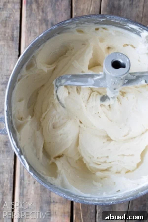 Cupcake batter ingredients being blended together in an electric mixer bowl.