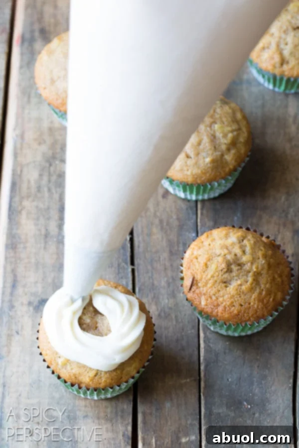 A piping bag skillfully decorating baked cupcakes with swirls of frosting.