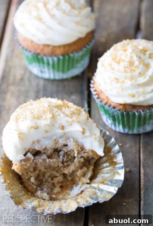 A close-up of a Hummingbird cupcake with a large bite taken out, revealing its moist texture and fruit pieces.