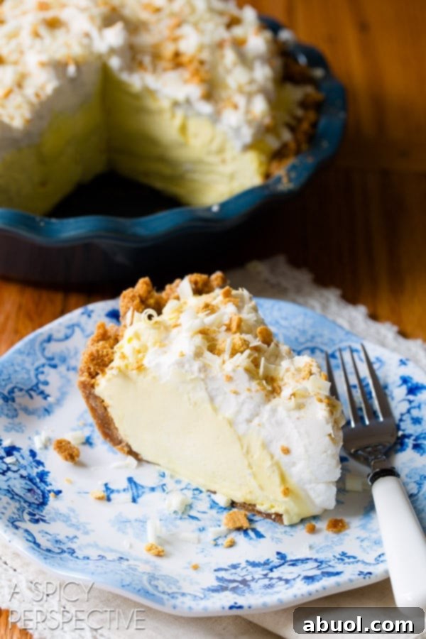 Slice of silky lemon cream pie on a plate with a fork, ready to be enjoyed.