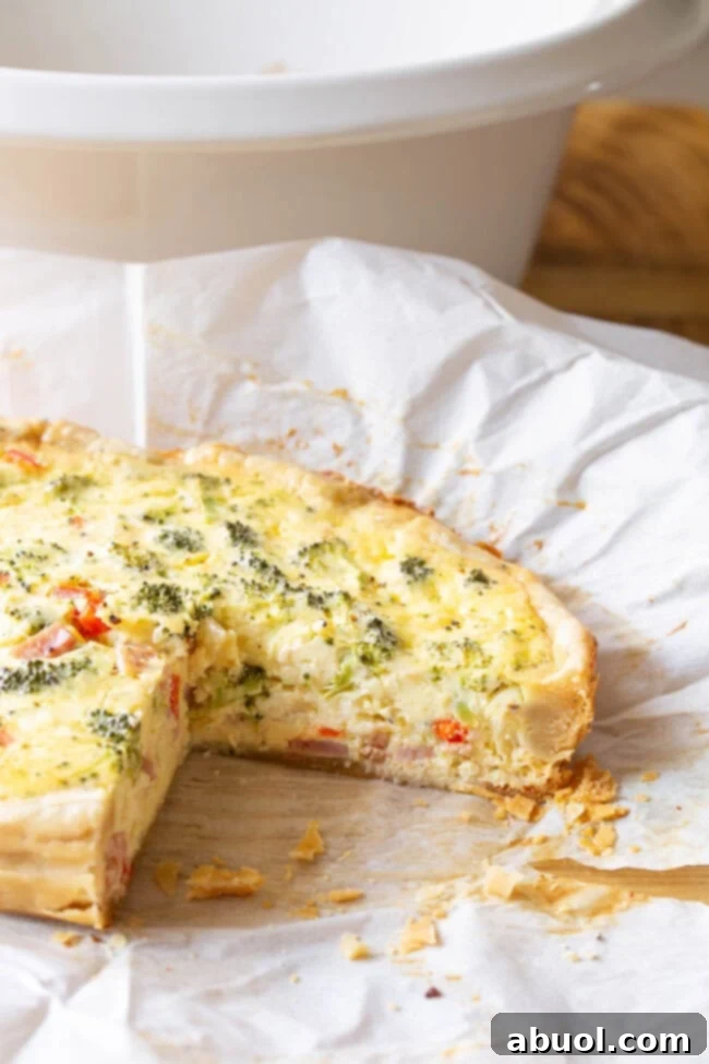 Side view of this quiche with a slice cut out on a piece of parchment paper.