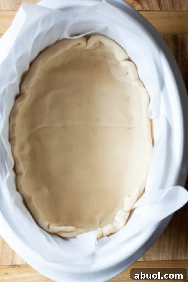 Top down shot of pie dough spread into the crockpot.