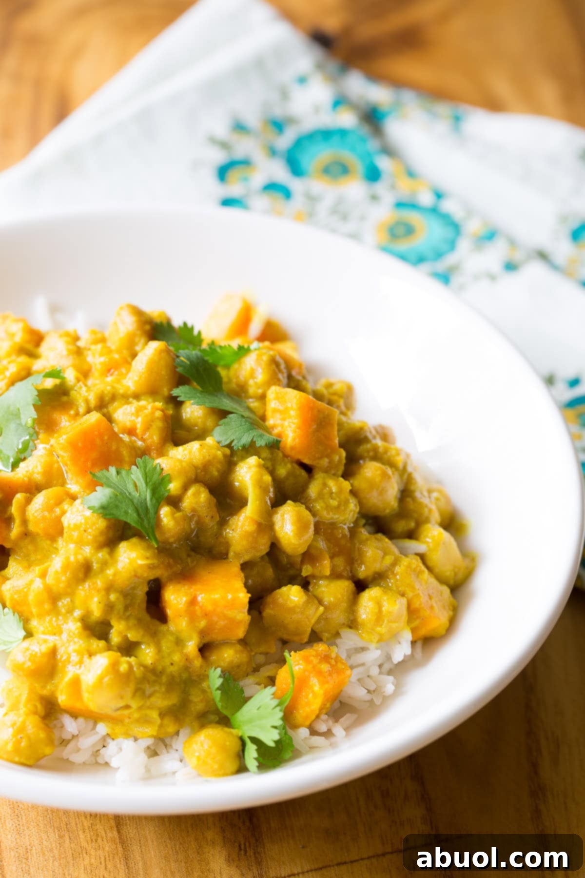 A white plate showcasing a serving of slow cooker chickpea curry on a bed of white rice, ready to be enjoyed.
