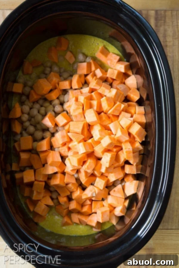 Crockpot with chopped sweet potato recently added, blending with the curry sauce and chickpeas.