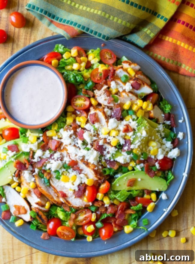Overhead shot of grilled chicken salad with a side of dressing.