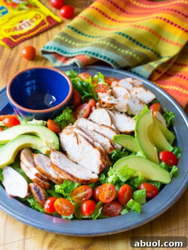 Loaded Mexican grilled chicken salad on a platter with an empty ramekin.