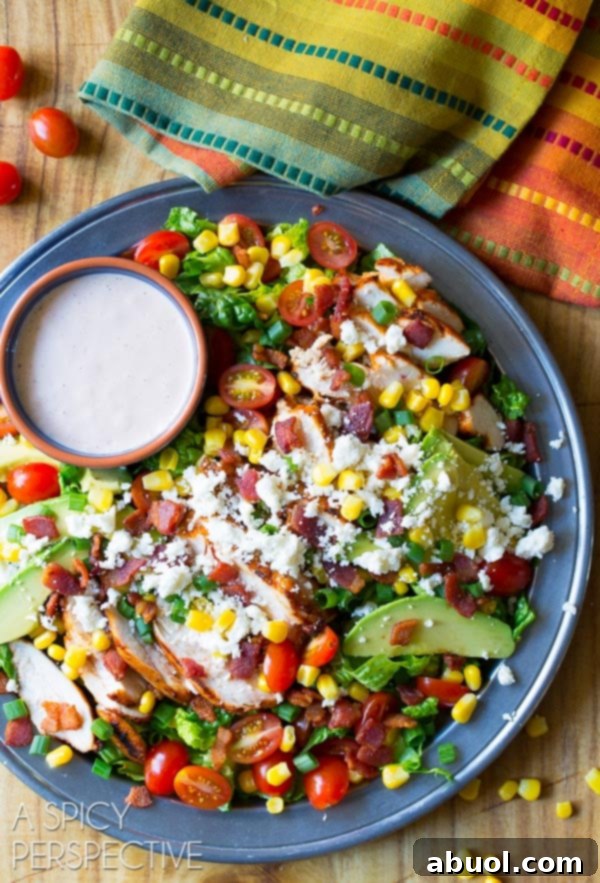 Overhead shot of large platter filled with completed Mexican grilled chicken salad and a ramekin filled with dressing.