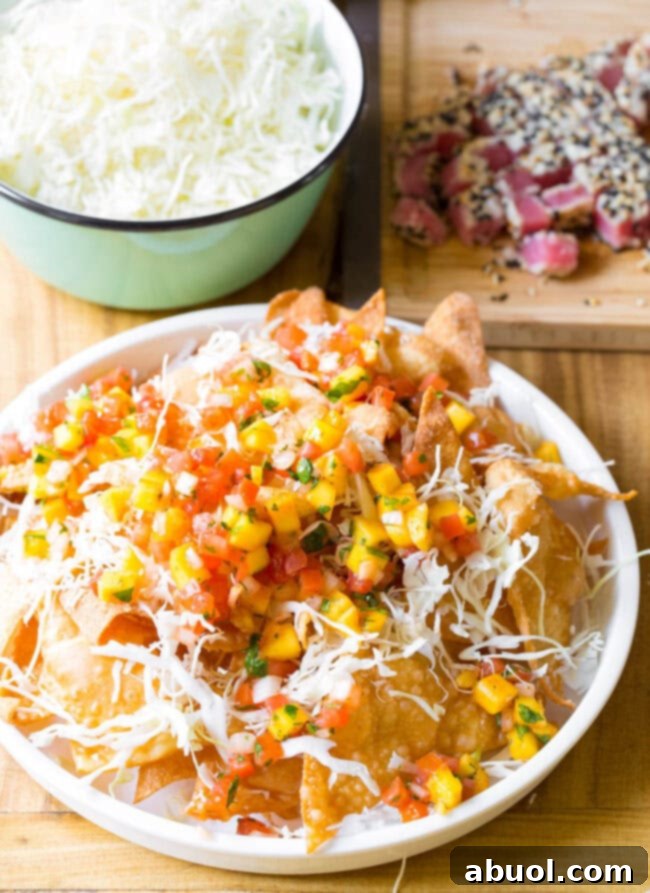 Crispy wonton chips on a white plate loaded with shredded cabbage and mango pico de gallo.