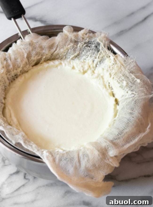 Crafting Creamy Ricotta from Scratch 10 Solidified homemade ricotta cheese in cheesecloth over a bowl.