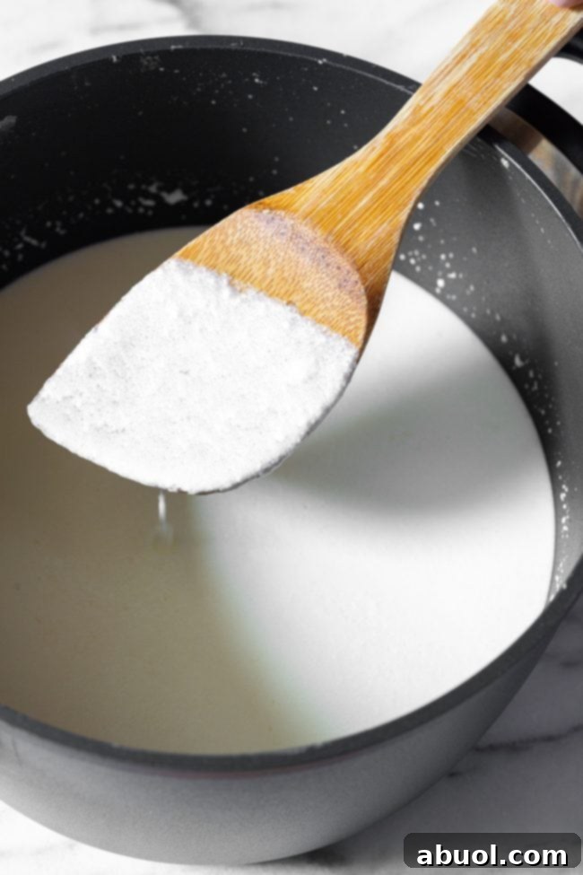 Crafting Creamy Ricotta from Scratch 6 Stirring milk mixture with a wooden spoon in a metal pot.