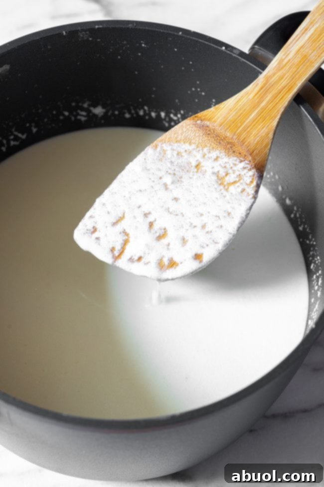 Crafting Creamy Ricotta from Scratch 7 Wooden spatula showing coating of cheese over cooking ricotta in a large black pot.