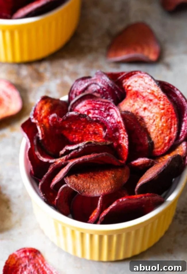 Top view of perfectly crispy oven-baked beet chips served in a vibrant yellow ramekin, ready for snacking.