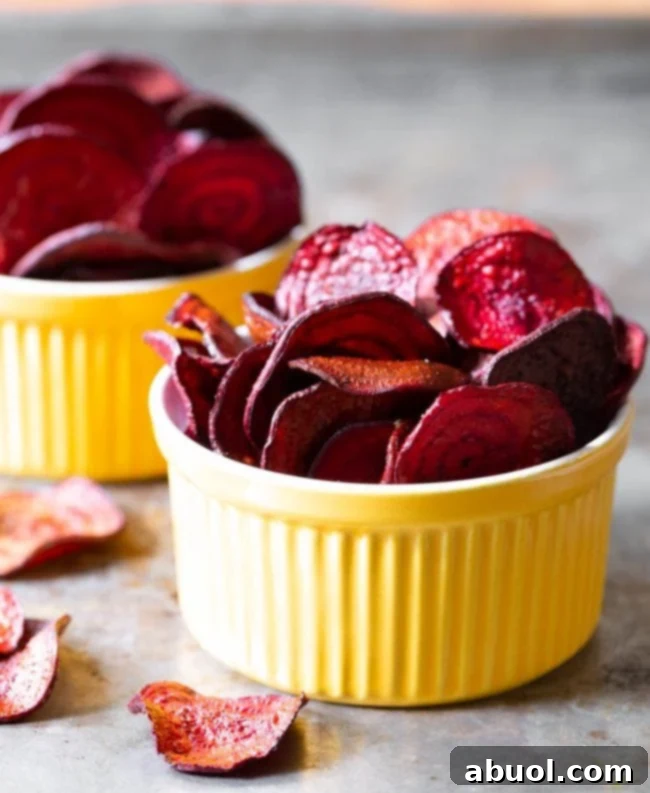 A final, beautifully presented shot of vibrant, perfectly crisp oven-baked beet chips, ready to be devoured, served in bright yellow bowls.