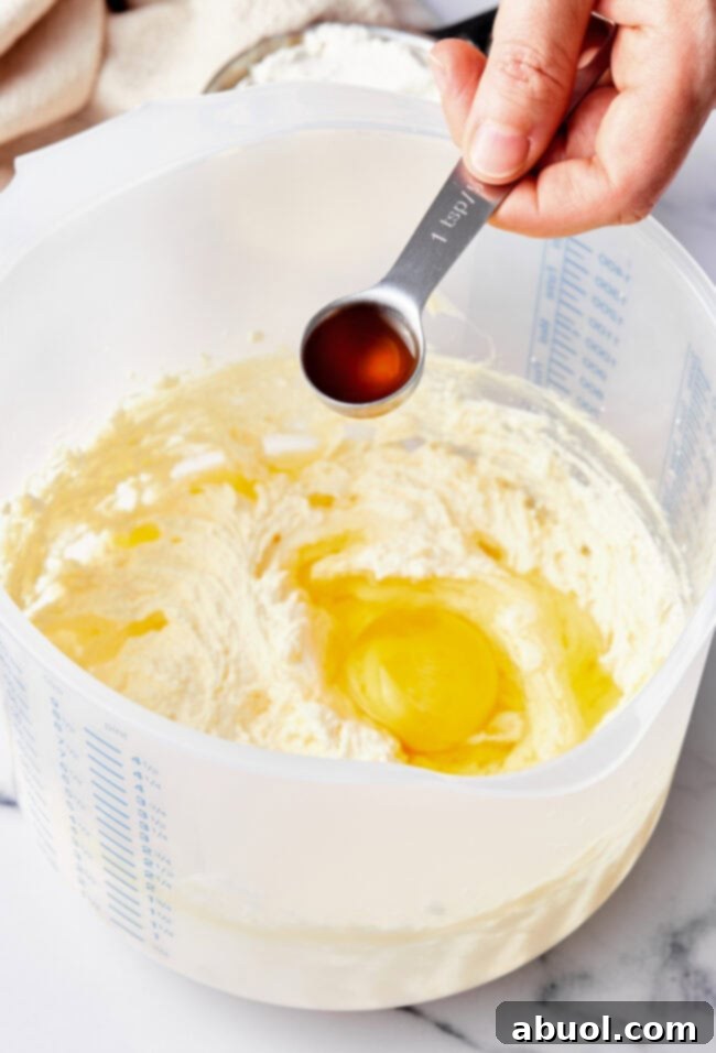 A hand adding vanilla to a mixing bowl with muffin batter.