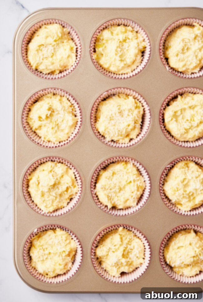 Muffin batter scooped into the cups of a muffin tin.
