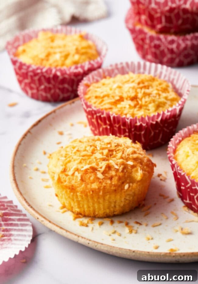 Tropical breakfast muffins on a white plate. The front muffin has the wrapper taken off.