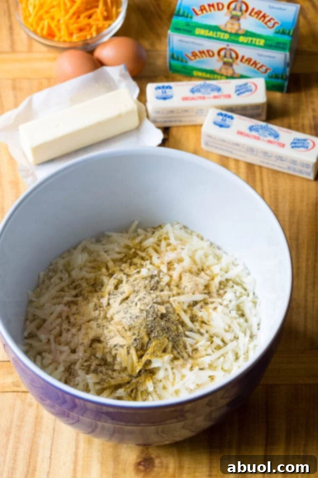 Close-up of shredded potatoes mixed with a blend of vibrant spices in a large mixing bowl.