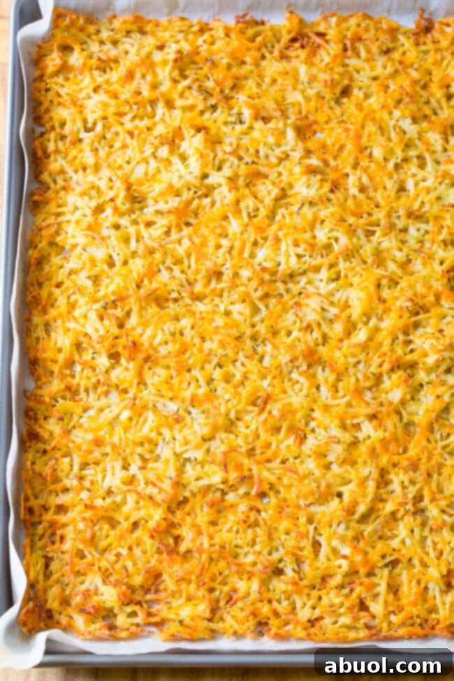 A perfectly golden brown, crispy oven-baked hash brown sheet on a baking pan, fresh from the oven.