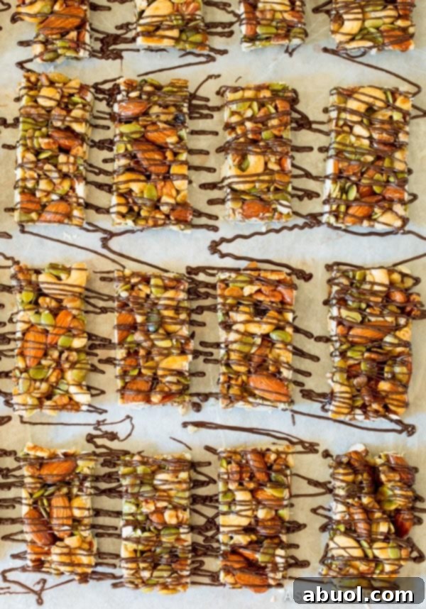 Top down view of 16 nut bars drizzled with chocolate on parchment paper.
